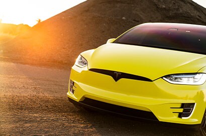 Yellow Tesla SUV at sunset on desert road
