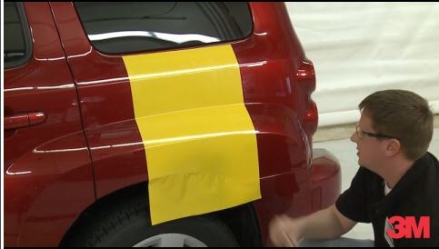 3M expert installer applying 3M car wrap on red car bumps and curves, showing ease of install.
