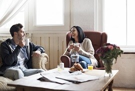 a couple relaxing in their living room with warm indoor temperatures because of 3M thinsulate window film
