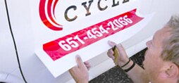 decal for one cycles company with logo and phone number being applied to a fleet vehicle
