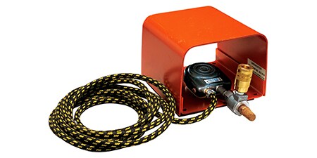 Image of an orange protective box containing a foot pressure switch to control adhesive application
