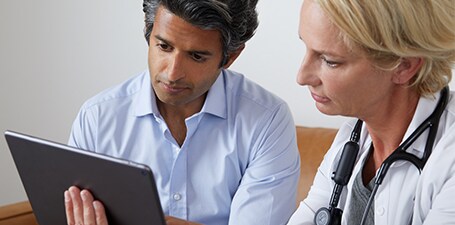 Clinician auscultating and showing man app on tablet
