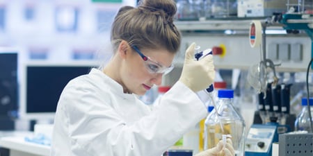 Woman in lab looking at a beaker
