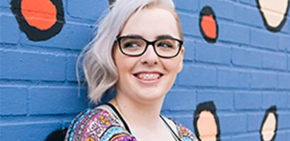 girl with clear braces and pink rubber bands smiling