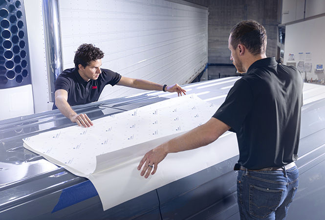 Technician installing 3M™ Cooling Film on a commercial vehicle roof
