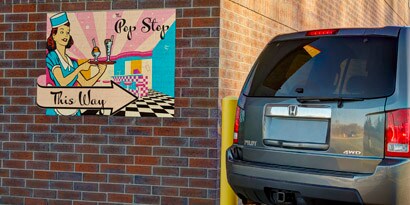 A wall graphic showing the direction of a Pop Stop store during the day using 3M reflective films.
