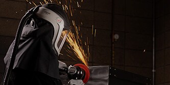 Worker wearing a PAPR and finishing steel.
