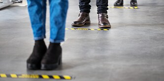 Someone waiting at a floor safety marker
