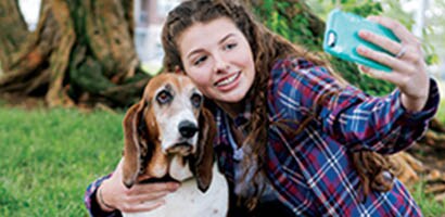 teen girl with clear braces taking selfie with dog outside