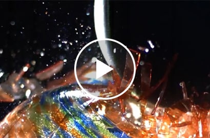 A weight smashing a glass ball after mechanical fasteners failed to hold metal panels together.