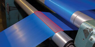 Blue film being processed in a factory machine
