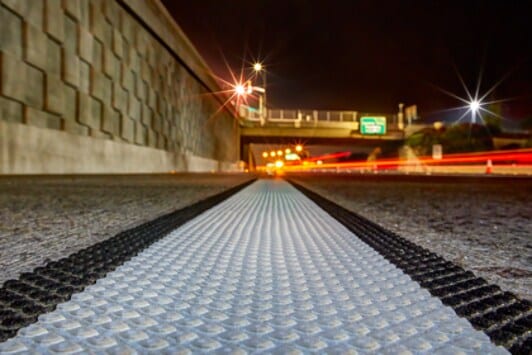 A blue car driving on a road next to white pavement marking line with black borders