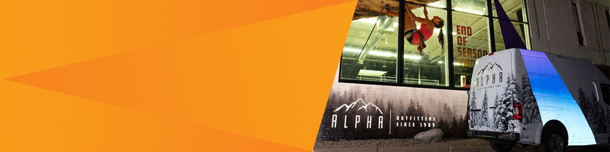 A graphic wrap on a van reflects blue and white light at night.
