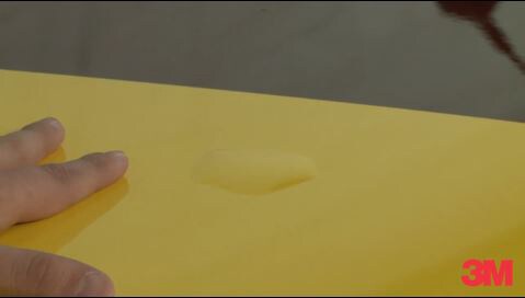 3M expert installer holding a 3M car wrap down to demonstrate how to remove bubbles when installing the car wrap.
