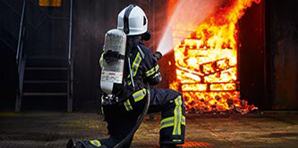 firefighter walking toward a burning house
