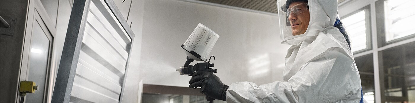 Person wearing PAPR and coveralls applying industrial paint
