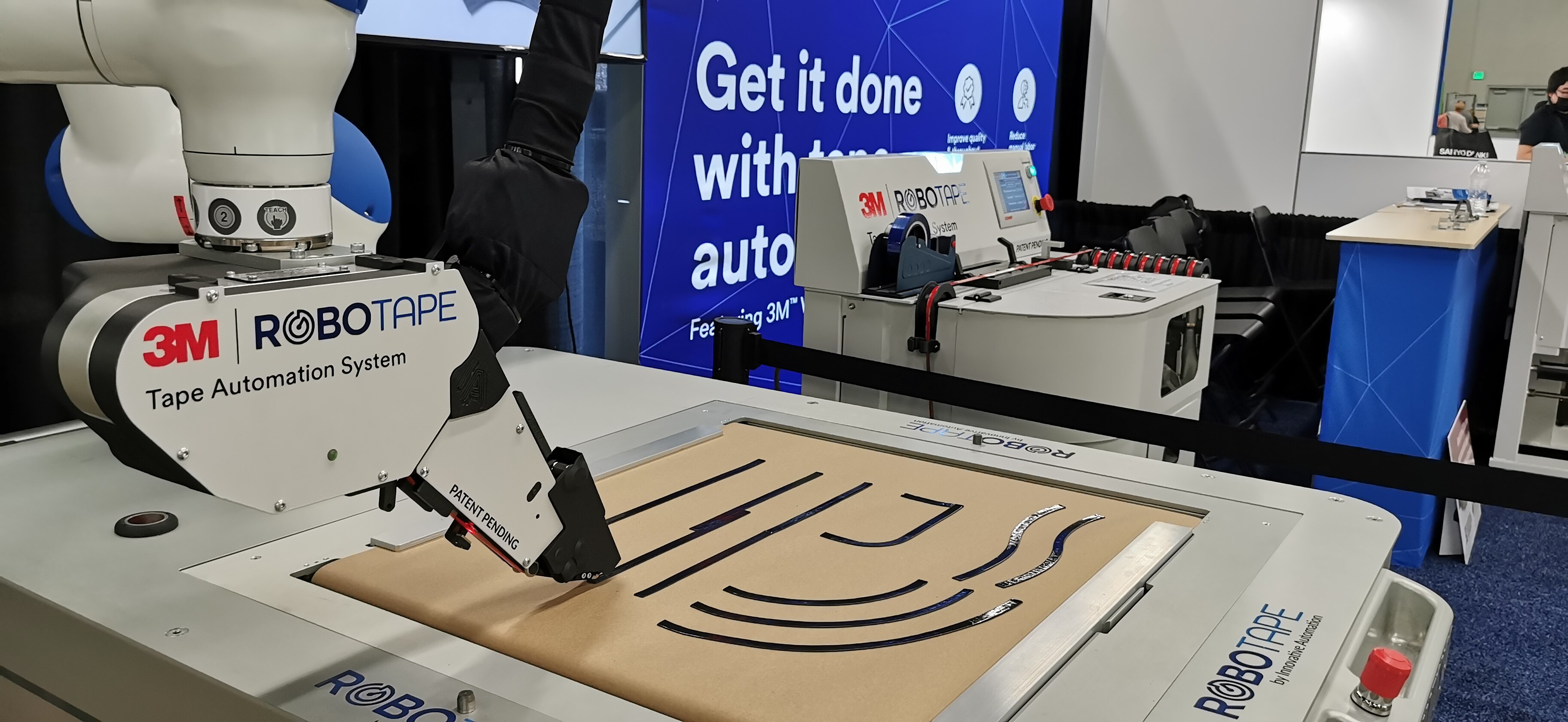 Image of two yellow robot arms, each with a RoboTape application head attached